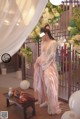 A woman in a pink dress standing in front of a table.