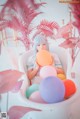 A woman sitting in a bathtub filled with colorful balloons.