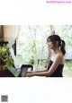 A woman in a black dress playing a piano.