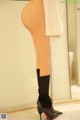 A woman in black stockings and high heels standing in front of a mirror.