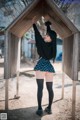 A woman in a skirt and stockings standing in front of a wooden structure.