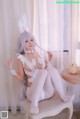 A woman in a white bunny costume sitting on a chair.