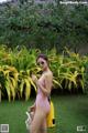 A woman in a pink bathing suit holding a yellow bag.