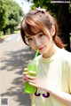 A young woman holding a green drink in her hand.