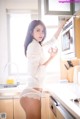 A woman in a white shirt and panties standing in a kitchen.